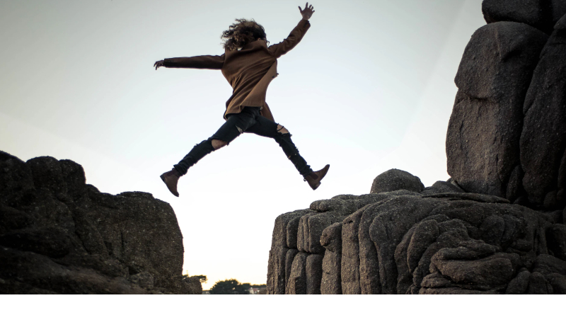 A person leaps from one rock to another