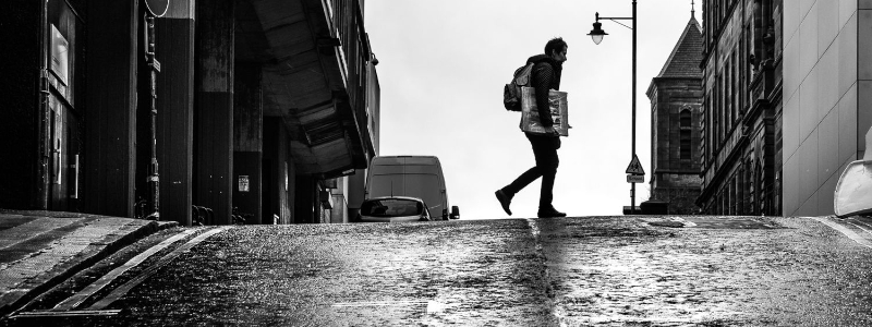 Black and white photo of a person crossing a street